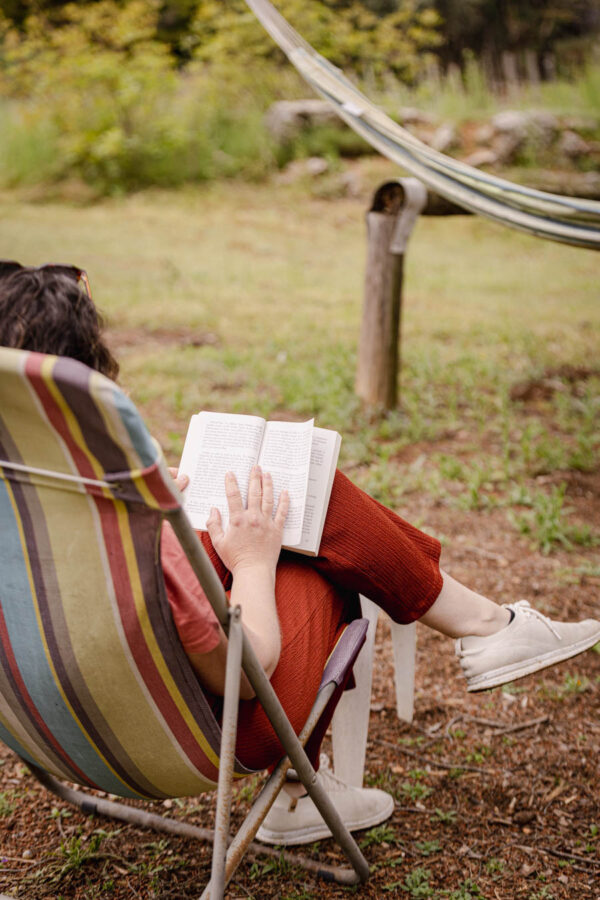 Femme assise sur une chaise détente, savourant un moment de lecture cocooning en pleine nature