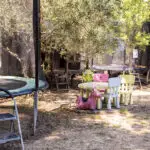 Aire de jeux extérieure avec trampolines, tables, chaises et cabane pour enfants à la mini-ferme.