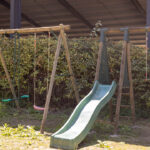 Aire de jeux extérieure avec balançoire et toboggan.