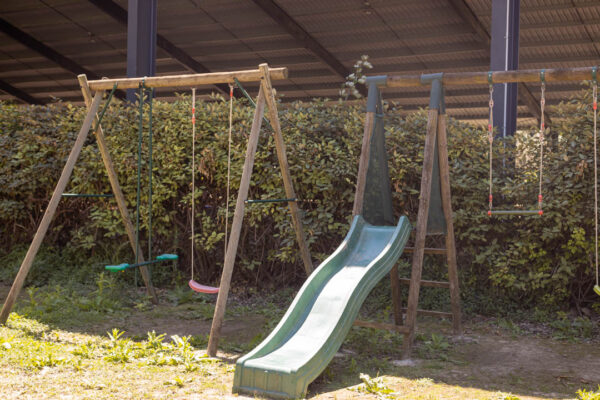Aire de jeux extérieure avec balançoire et toboggan.
