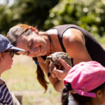 Perrine, l’animatrice, présente une tortue aux enfants émerveillés, tous captivés par la découverte de cet animal fascinant.