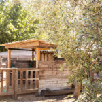 Enclos d’une mini ferme entouré de verdure, avec des animaux en plein air.